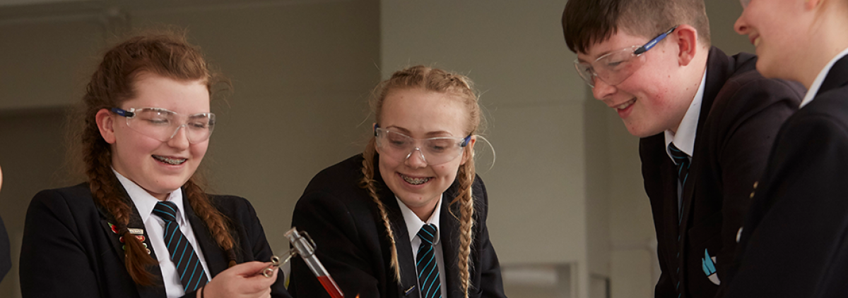 Students in science holding a test tube above a Bunsen burner.