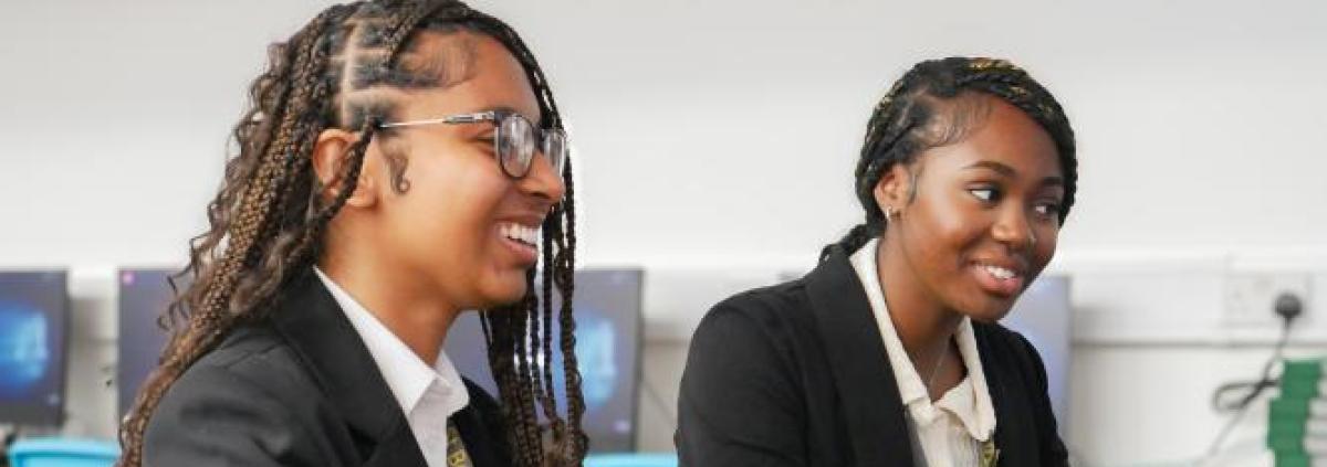 Two black female students are working on computers and smiling